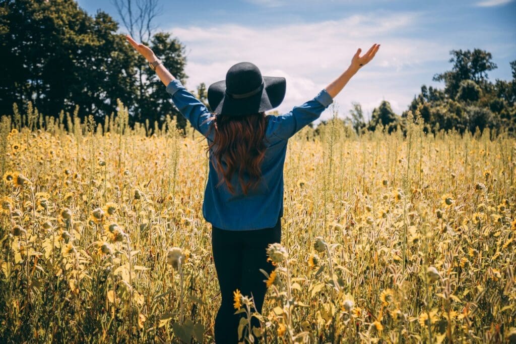 Woman joyfully throwing her arms in the air as she practices her mindset and mantras 