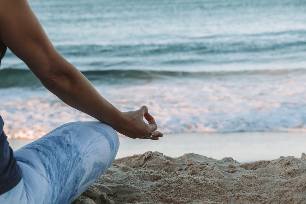 Woman meditating on the beach, taking a moment to motivate and inspire herself for the day 