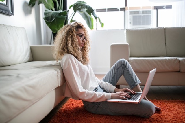 Soulful creative sits on the floor of her living room to write her soulful copy to serve her soulmate clients with her copy. 