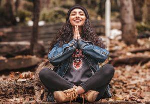 Woman holds her hands together in meditation, smiling with trust in her resilience 