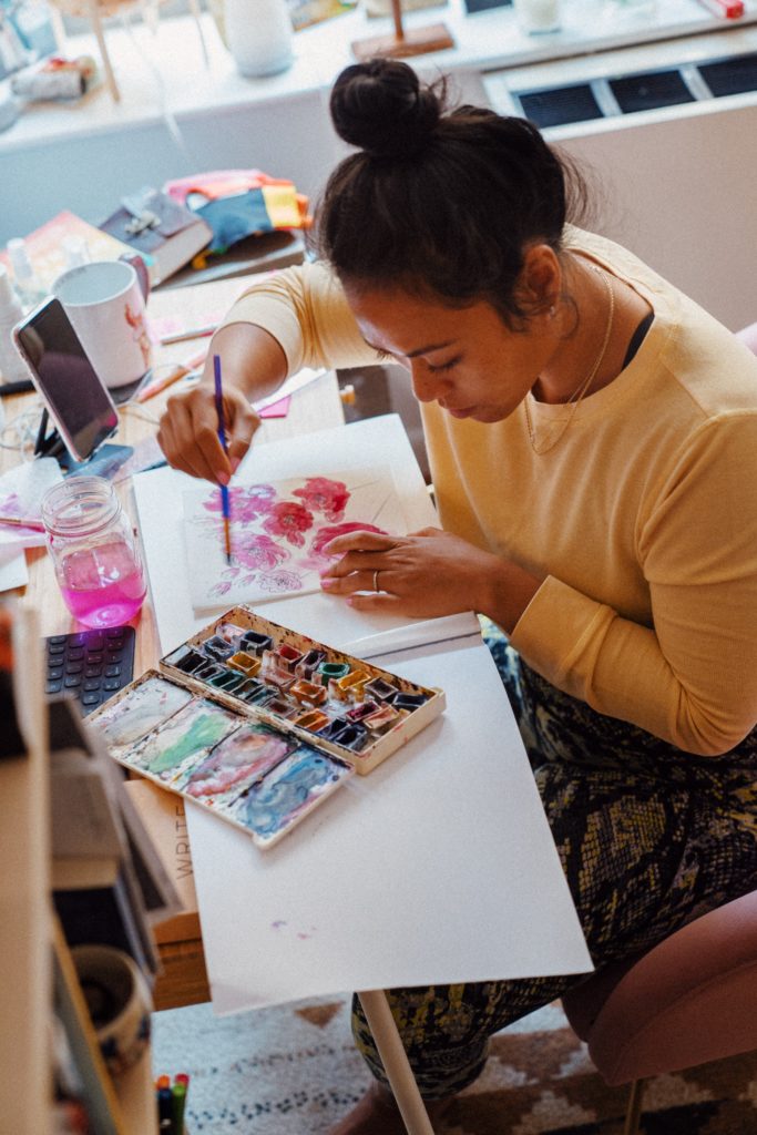 Image shows woman painting with water colours as a way of creatively raising her emotional awareness 