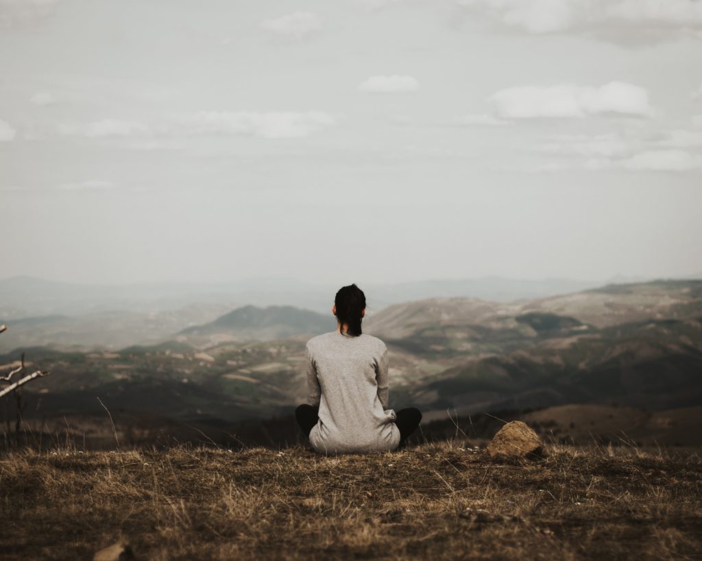Woman meditates outside, and is able to use her brain's neuroplasticity to transform her mindset and create sustainable change 