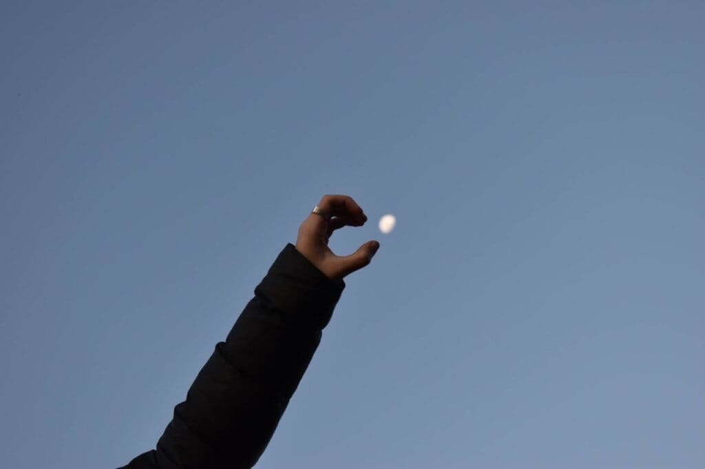 Woman cupping her hand around the moon 